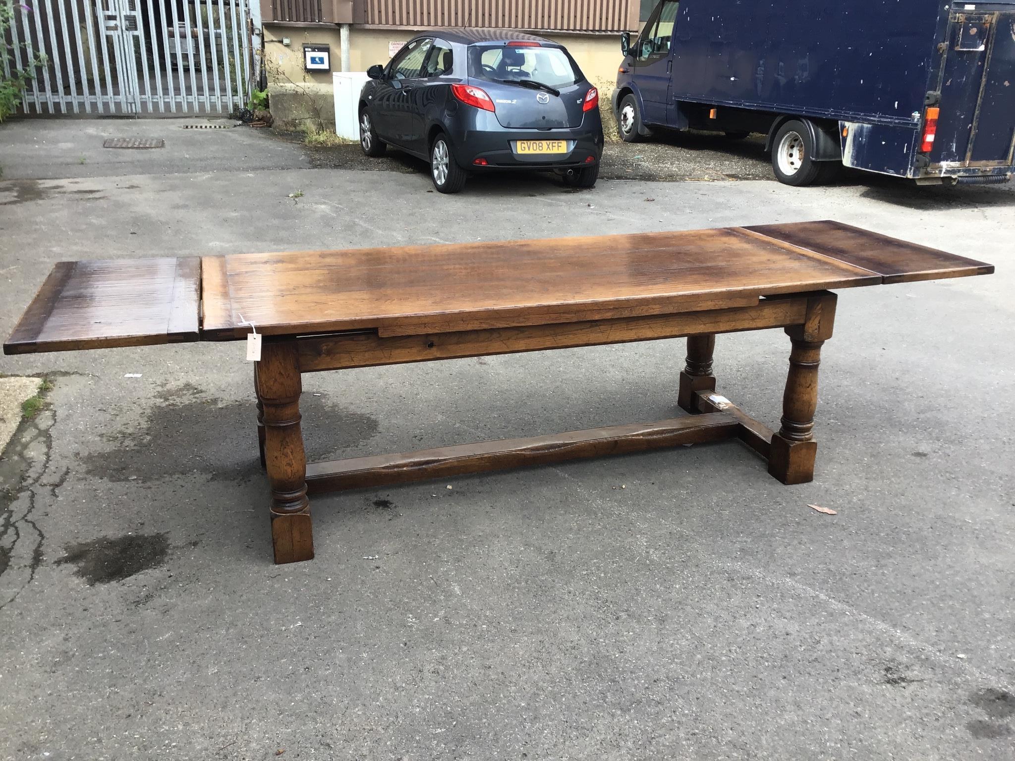 A reproduction 18th century style oak draw leaf refectory dining table with central stretcher, length 300cm extended, width 91cm, height 73cm
